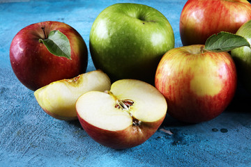 Ripe red apples with leaves on wooden background.