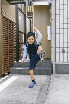 小学生の男の子が玄関から元気に飛び出す