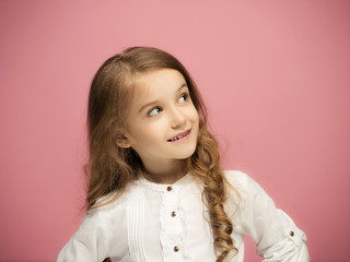 The happy teen girl standing and smiling against pink background.