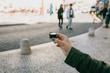 A woman's hand holds a glass made of chocolate in which traditional Portuguese liqueur is tinted named Ginjinha and prepare to drink