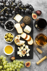 Snacks with wine - various types of cheeses, figs, nuts, honey, grapes on a gray background. Top view. Food background