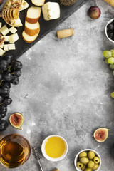 Snacks with wine - various types of cheeses, figs, nuts, honey, grapes on a gray background. Top view, copy space. Food background