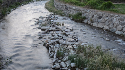Shining river with boulders & foliage