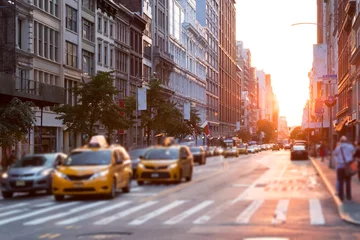 Fotobehang New York taxi Zonlicht schijnt in een drukke straat in New York City met taxi& 39 s die op het kruispunt stoppen