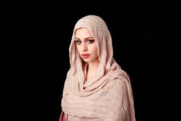 portrait of pretty girl wearing a pink headscarf. black studio background.
