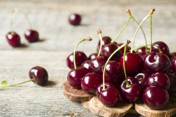 Juicy ripe cherries with twigs on wooden stand on rustic background