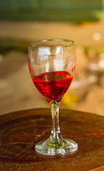 glass of red wine is placed on a wooden table. In the morning sea atmosphere of the summer.