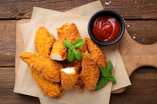 Delicious crispy fried breaded chicken breast strips with ketchup.