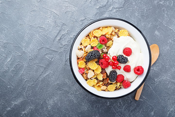 Healthy breakfast. Fresh granola, muesli with yogurt and berries on gray background. Top view. Copy space.