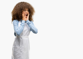 African american shop owner woman wearing an apron stressful keeping hands on head, terrified in...