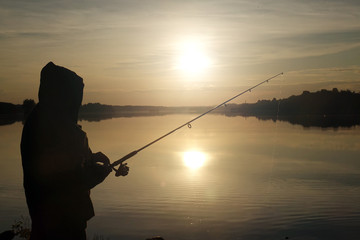 Fisherman silhouette at sunset. hobby, sport.