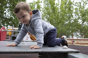 Fototapeta premium Child under two years playing in the park with a gray jacket and blue pants.