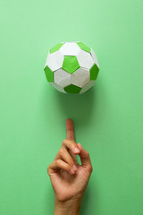 Paper soccer ball on soccer field or green background. Origami. Paper craft. Soccer game concept.