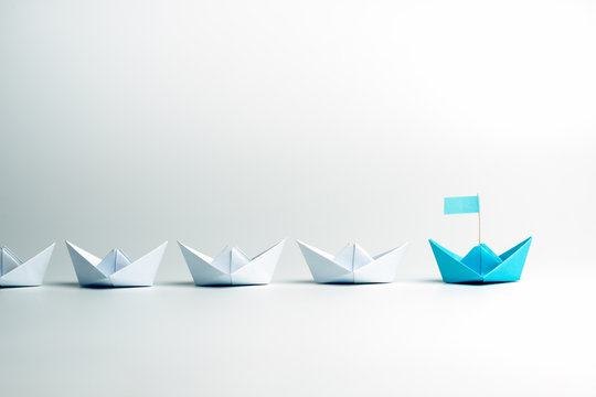 Leadership concept. Blue leader paper ship leading among white on white background.