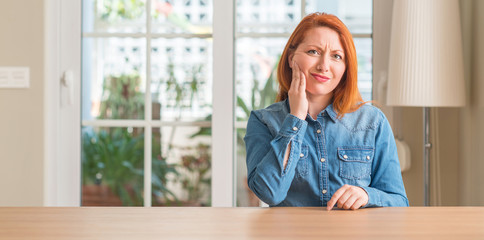 Redhead woman at home touching mouth with hand with painful expression because of toothache or dental illness on teeth. Dentist concept.