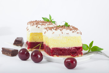 Delicious homemade cherry cake with vanilla and whipping cream. Decorated with mint leaves and chunk of chocolate. Isolated on white background.
