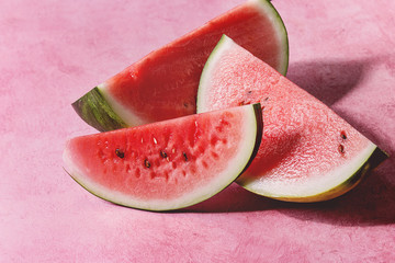 Ripe sliced watermelon over pink texture background. - obrazy, fototapety, plakaty