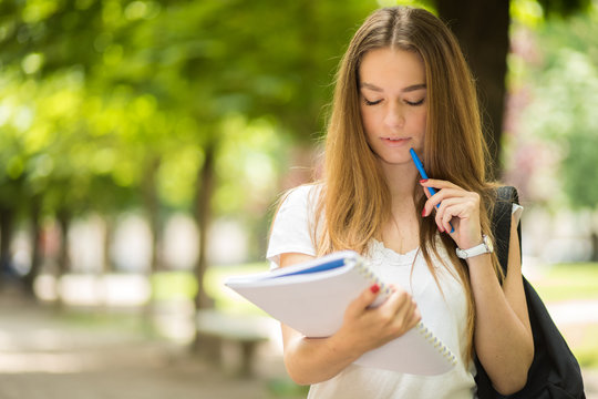Female student reading a book outdoor in the park