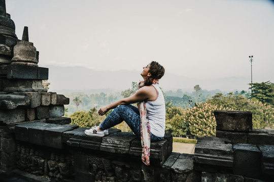 Beautiful young tourist feeling the peace of the great Borobudur temple, historical famous place in the java island Indonesia. Lifestyle and travel photography.