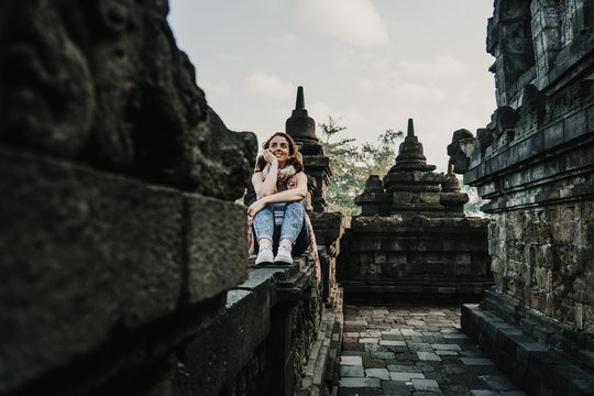 Beautiful young tourist feeling the peace of the great Borobudur temple, historical famous place in the java island Indonesia. Lifestyle and travel photography.