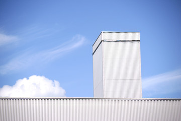 Dachkante Industriehalle / Die Dachkante einer Industriehalle aus Wellblech vor einem blauen Himmel...