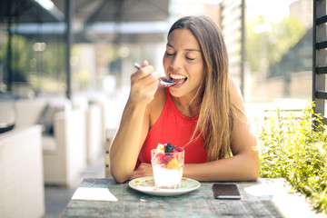 Beautiful girl eating a dessert in a bar