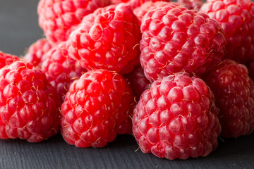 Fresh and tasty looking raspberries on a black wooden table