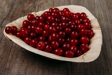 fresh red cherries in a wooden plate on a wooden table. wooden plate on a wooden background. a plate in the form of a triangle. ecology. proper nutrition.