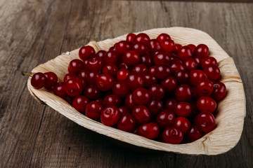 fresh red cherries in a wooden plate on a wooden table. wooden plate on a wooden background. a plate in the form of a triangle. ecology. proper nutrition.