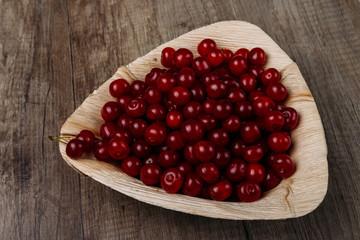 fresh red cherries in a wooden plate on a wooden table. wooden plate on a wooden background. a plate in the form of a triangle. ecology. proper nutrition.