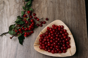 fresh red cherries in a wooden plate on a wooden table. wooden plate on a wooden background.