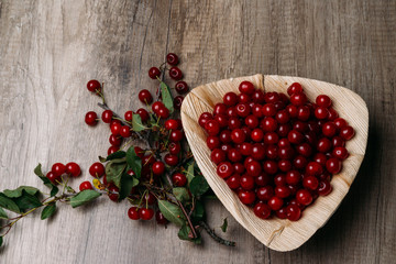 fresh red cherries in a wooden plate on a wooden table. wooden plate on a wooden background.