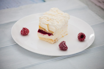 Dessert of cake and raspberries on a large white plate on a napkin in blue stripes
