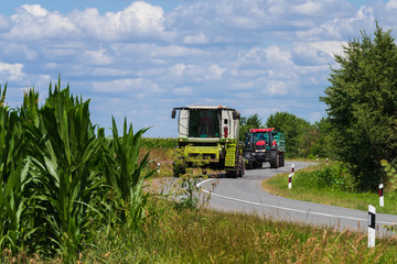 The tractor and combine are moving towards the field