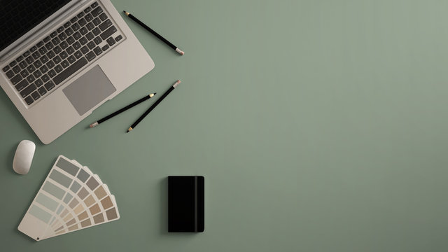 Stylish minimal office table desk. Workspace with laptop, notebook, pencils and sample color palette on dark green background. Flat lay, top view
