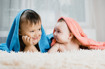 Brother and sister lie with towels on their heads, family love, younger and older