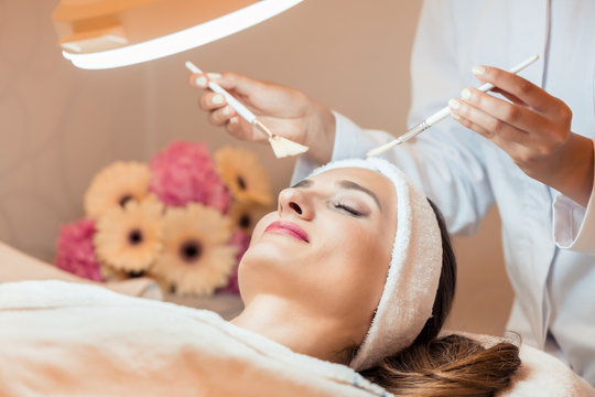 High-angle close-up view of the face of a beautiful woman during anti-aging facial massage with soft brushes in a modern cosmetic center