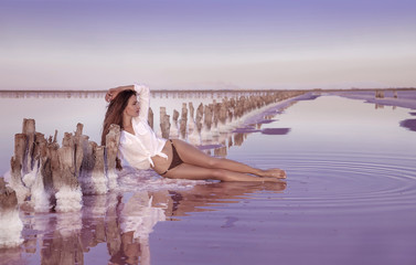 Beautiful free sexy girl in white swimwear posing on salty beach at sunset. Sensual tanned woman...
