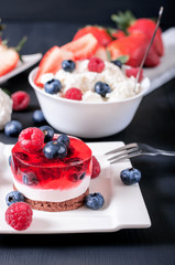 Proper nutrition, jelly cake, cottage cheese with fruit on a black wooden background