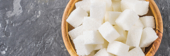 wooden bowl with white sugar cubes on dark background banner