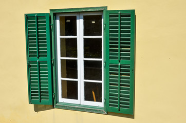 Green window with shutters in Mediterranean style on yellow wall. Vintage background. Cyprus, Nicosia.