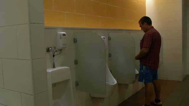 A man uses a urinal in the toilet