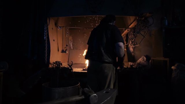 The smith lights the fire in the furnace to heat the metal