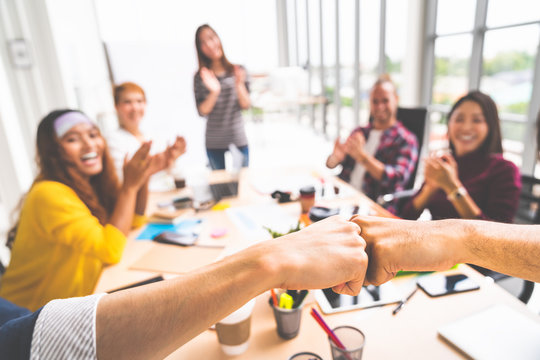 Business partners or men coworkers fist bump in team meeting, multiethnic diverse group of happy colleagues clapping hands. Teamwork cooperation, team building, or success business project concept