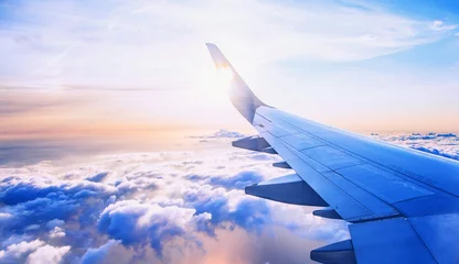 Foto op Plexiglas vliegen en reizen, uitzicht vanuit vliegtuigraam op de vleugel op zonsondergangtijd © babaroga