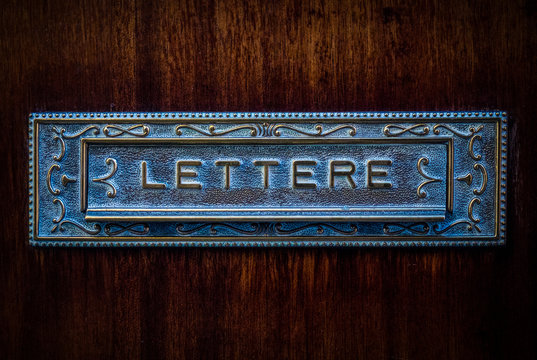 Vintage italian metal mailbox in wooden door, text lettere