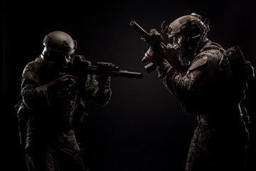 soldiers or private military contractors holding rifle. Image on a black background. war, army,...