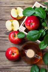 Apple cider vinegar and fresh red apple on a wooden background