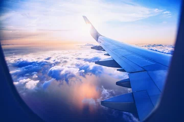 Gordijnen vliegen en reizen, uitzicht vanuit het vliegtuigraam op de vleugel op zonsondergangtijd © babaroga