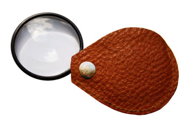 Ancient pocket magnifier in a brown leather holster, with the reflection of the sky in the glass.